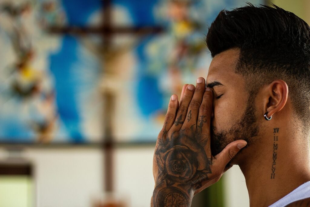 pexels-photo-1309052-1309052 A man with tattoos prays inside a church, capturing a moment of reflection and spirituality.